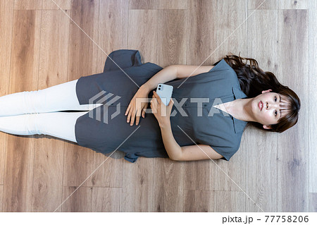 フローリングに寝転がってスマホを使う眼鏡の女性の写真素材85964242- PIXTA