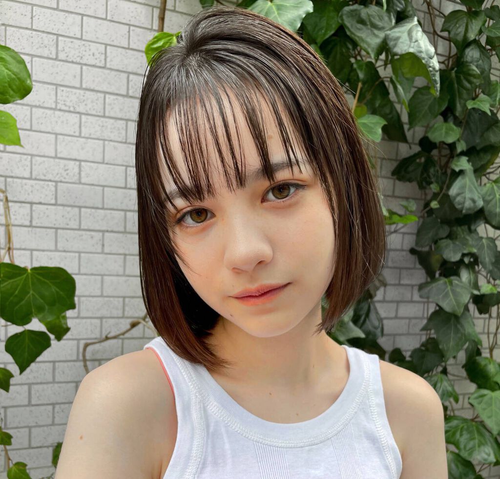 長いブロンドの髪と優しい笑顔で、喜びのために目を閉じている美しい女性。あごの下で陽気な女性が手を握って、顔の表情を喜んでいます。顔の表情と前向きな感情無料写真