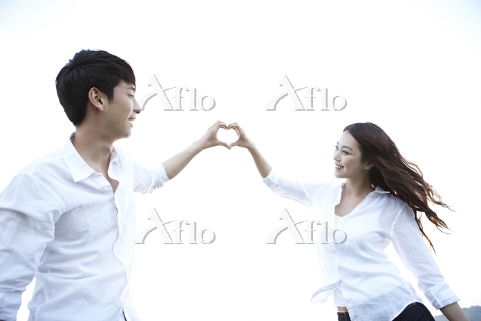 手女性と男性は心です手美しい若いカップルは指のハートを作っています手ハート カップル手でハートの形を作るカップルのクローズ アップPremium写真