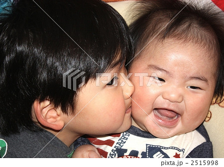 幸せかわいい女の子抱擁双子の妹のクローズアップ顔と頬に彼女にキス。二人の姉妹は抱き合ってお互いの頬にキス。姉は妹の頬にキスをする。家族と健康.645734232