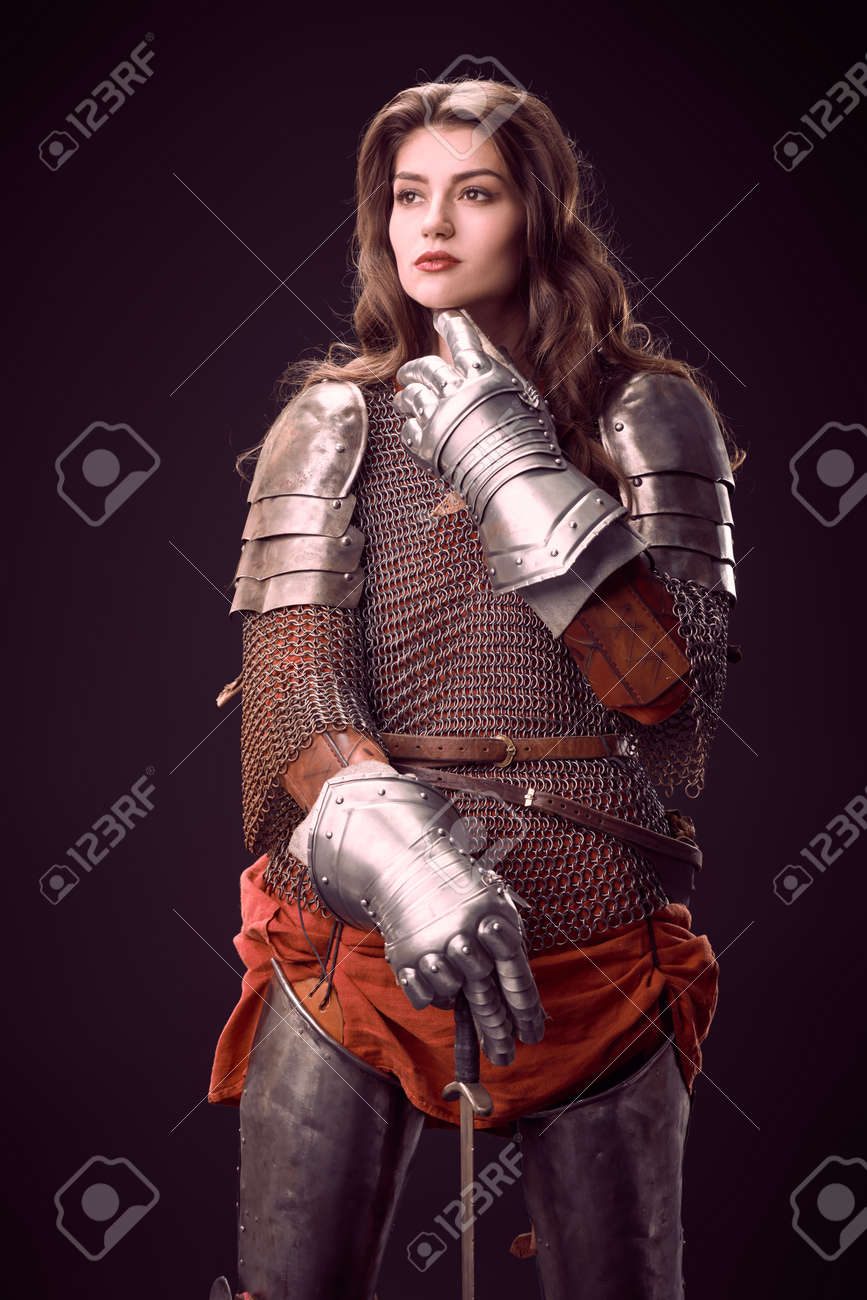 プレートアーマーの魅力的な女性騎士が剣でポーズをとる。中世の騎士。黒の背景にスタジオポートレート。の写真素材・画像素材 Image 164538782