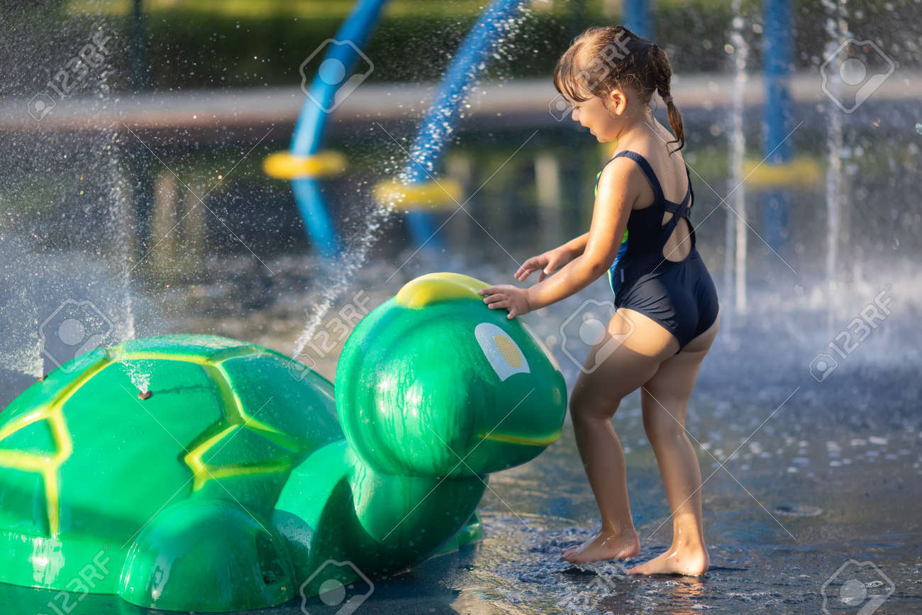 水遊び場で公園で水遊びを楽しんでいる小さな女の子。夏の日の写真素材・画像素材 Image 141048868
