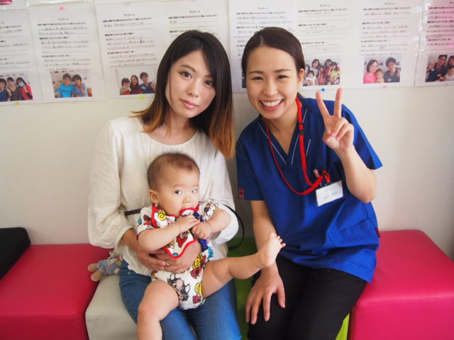 お母さんの膝の上にのる0歳児の赤ちゃんとそれを見守る父親と祖父母の5人の家族 65090004180 の写真・イラスト素材アマナイメージズ