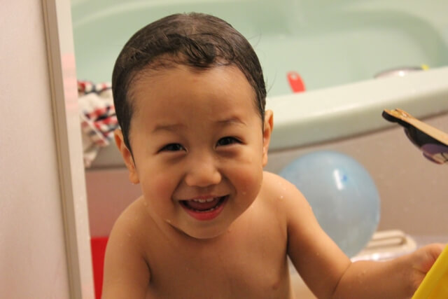 赤ちゃんの入浴と衛生。幼児の世話をします。 2人の陽気な姉妹が白い赤ちゃんのお風呂で入浴し、石鹸の泡の中で遊ぶPremium写真