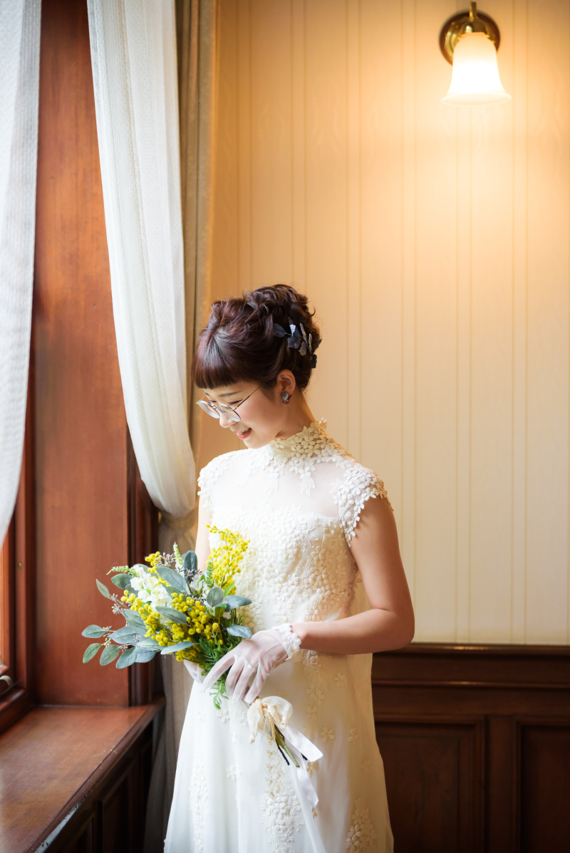 緑の花嫁介添人ブーケを保持している眼鏡の白い美しいドレスを着ている若い笑顔の完璧な女性の花嫁の肖像画Premium写真